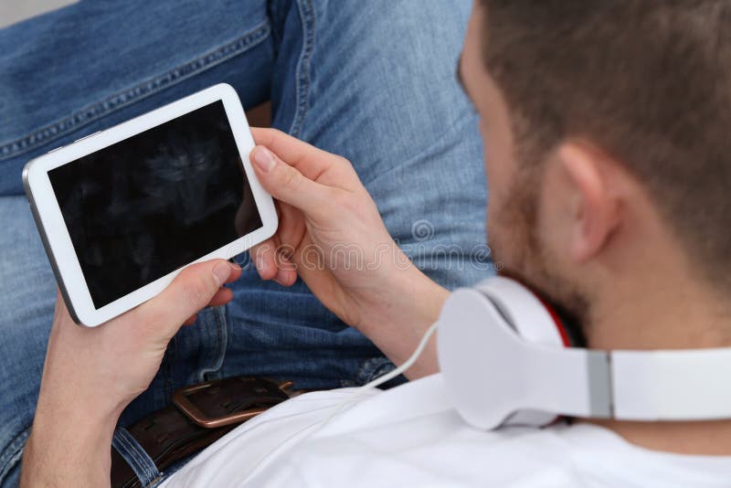Junger Mann, der Musik auf seinem Tablet-Computer hört lizenzfreie stockbilder Junger Mann, der Musik auf seinem Tablet-Computer hört lizenzfreie stockbilder