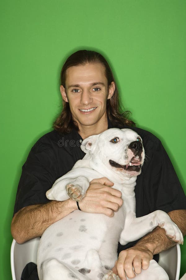 Junger Mann, der weißen Hund auf Schoss anhält. lizenzfreie stockfotos Junger Mann, der weißen Hund auf Schoss anhält. lizenzfreie stockfotos