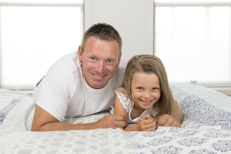 Junger Mann, der zu Hause auf Bett zusammen mit entzückenden 7 Jahren alten Spielen des kleinen Mädchens glücklich im Familienvat stockfoto Junger Mann, der zu Hause auf Bett zusammen mit entzückenden 7 Jahren alten Spielen des kleinen Mädchens glücklich im Familienvat stockfoto