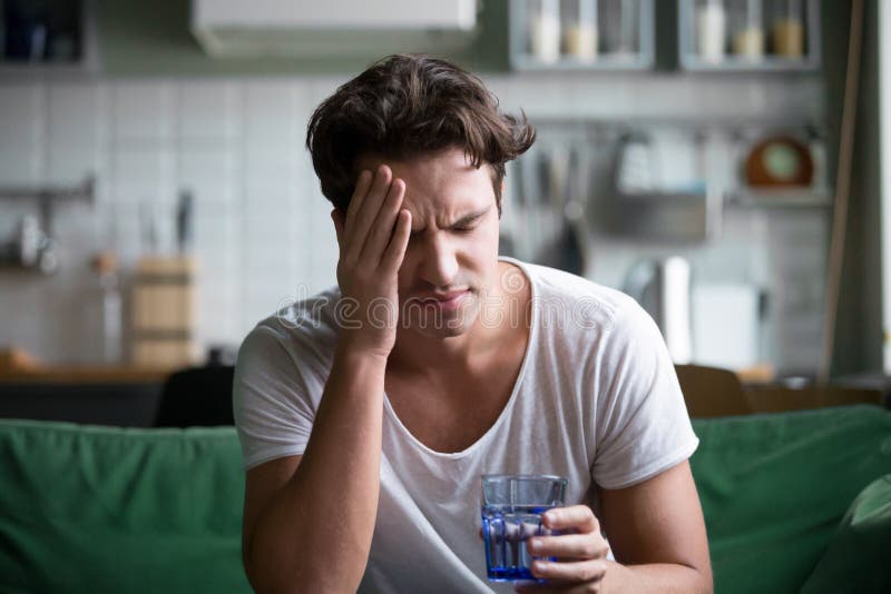Junger Mann, der zu Hause unter Kopfschmerzen, Migräne oder Kater leidet