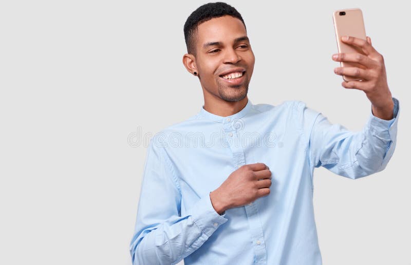 Junger Mann glücklicher Afrikaner Amerfican hält das moderne intelligente Telefon, online spricht und bloggt auf Mobiltelefon stockfotografie Junger Mann glücklicher Afrikaner Amerfican hält das moderne intelligente Telefon, online spricht und bloggt auf Mobiltelefon stockfotografie
