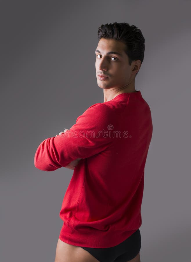 Junger Mann mit roter Wollstrickjacke und Unterwäsche, Arme gekreuzt lizenzfreies stockfoto Junger Mann mit roter Wollstrickjacke und Unterwäsche, Arme gekreuzt lizenzfreies stockfoto