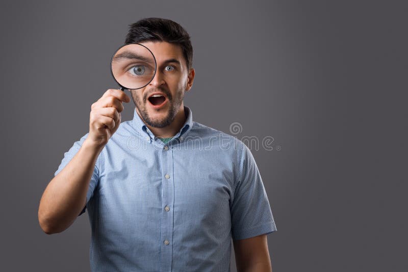 Junger Mann mit Vergrößerungsglas lizenzfreie stockfotografie