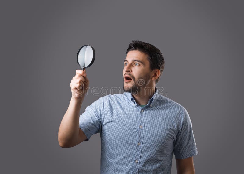 Junger Mann mit Vergrößerungsglas stockfotografie