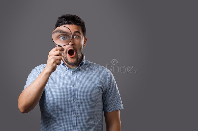 Junger Mann mit Vergrößerungsglas lizenzfreie stockbilder