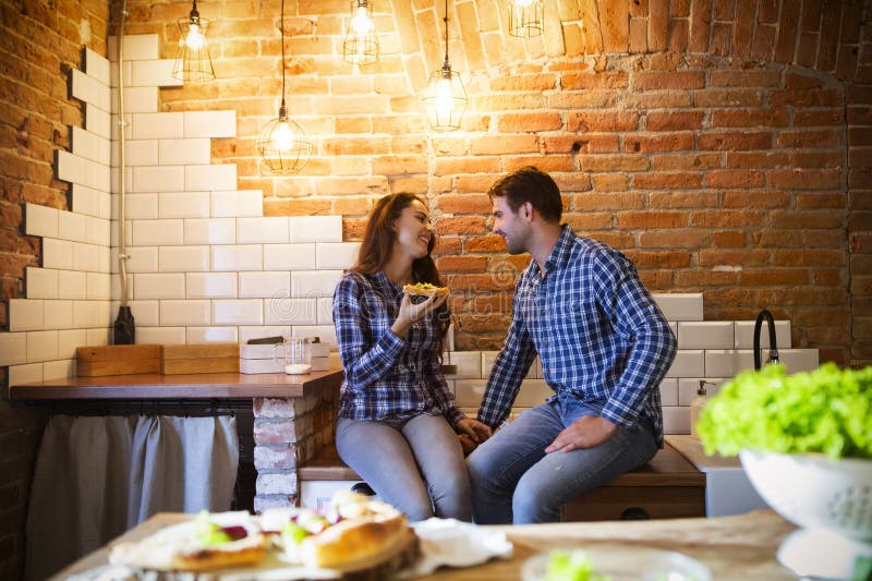 Junger Mann und Frau, die zusammen an der Küche kocht und isst stockfotografie Junger Mann und Frau, die zusammen an der Küche kocht und isst stockfotografie