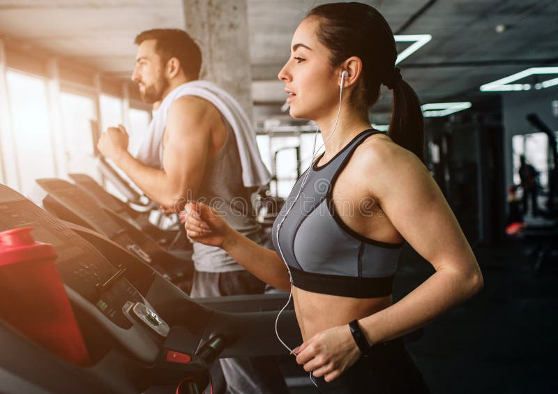 Junger Mann und Frau laufen auf der laufenden Maschine Sie tun diese Übung, jedes Mal wenn sie zum Fitness-Club kommen abschluß lizenzfreies stockbild