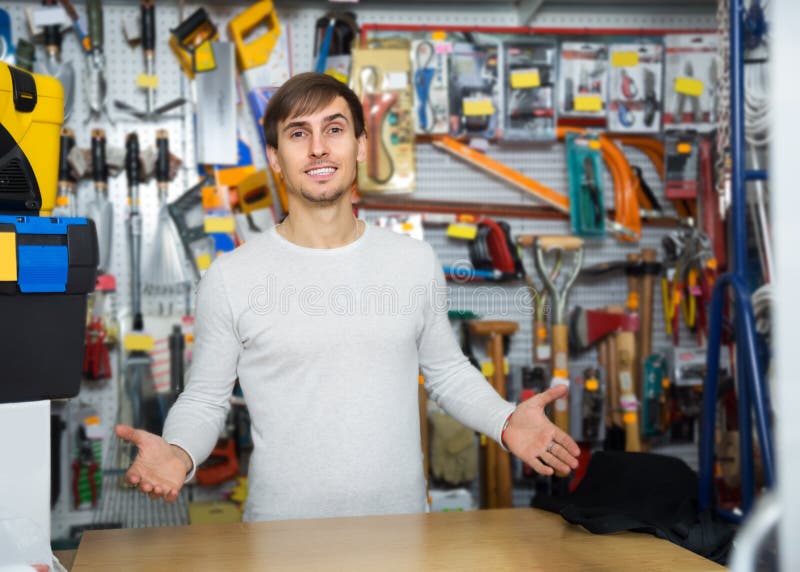 Junger männlicher Verkäufer, der am Werkzeugausstattungsabschnitt aufwirft lizenzfreie stockfotografie Junger männlicher Verkäufer, der am Werkzeugausstattungsabschnitt aufwirft lizenzfreie stockfotografie