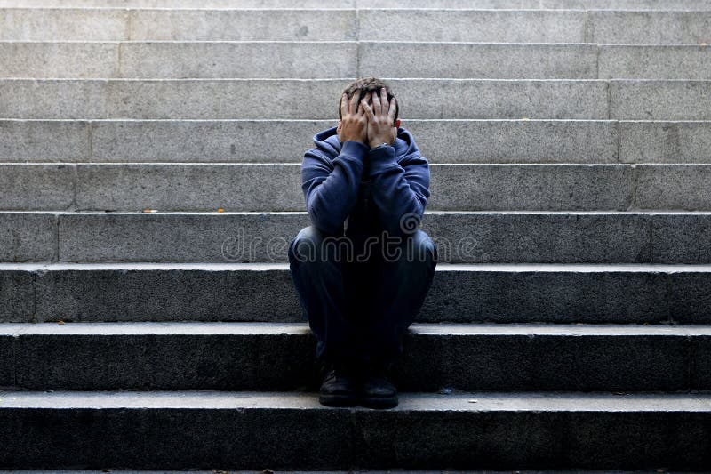 Junger obdachloser Mann verlor den Job, der in der Krise auf Boden Straßenbetontreppe sitzt