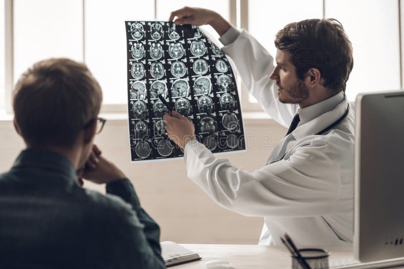 Junger Scan Doktor-Showing MRI des Gehirns zum Patienten lizenzfreies stockfoto Junger Scan Doktor-Showing MRI des Gehirns zum Patienten lizenzfreies stockfoto