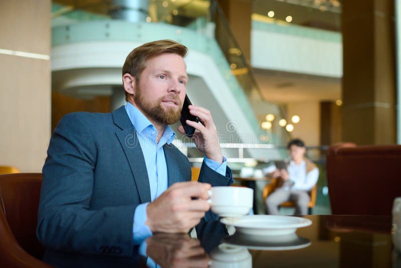 Junger selbstbewusster Unternehmer oder CEE im Bereich der Formalware, die auf dem Handy unterhalten lizenzfreie stockfotos