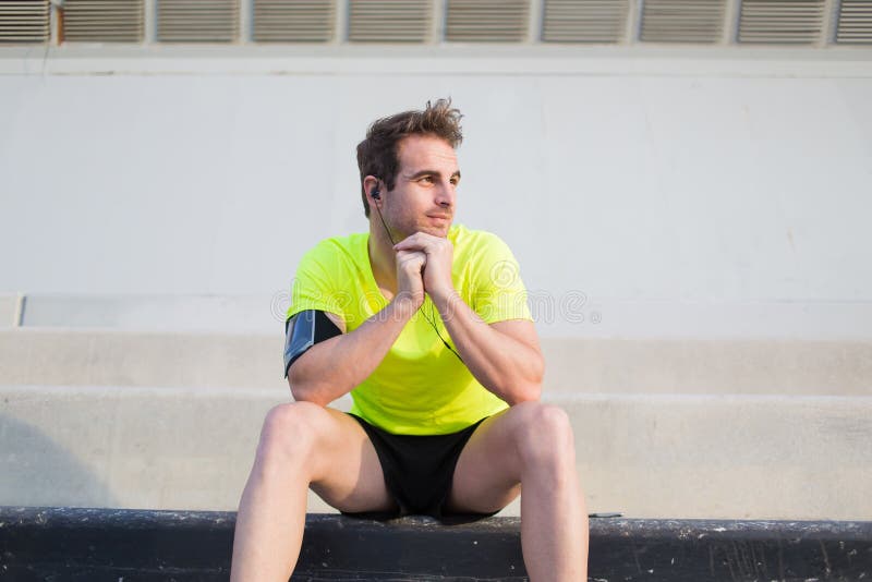 Junger Sport bemannt das durchdachte Schauen weg beim Haben eines Restes nach dem Training, das draußen in der städtischen Landsc stockfotografie Junger Sport bemannt das durchdachte Schauen weg beim Haben eines Restes nach dem Training, das draußen in der städtischen Landsc stockfotografie