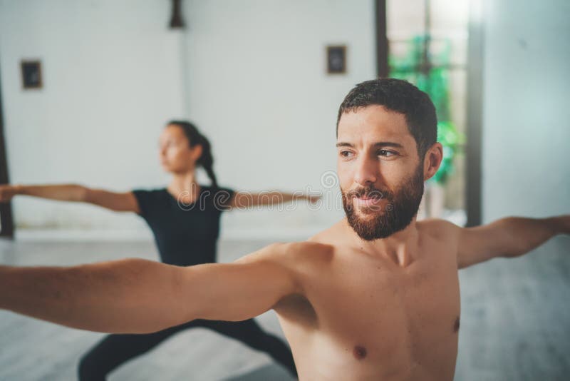 Junger sportiver Mann und Frau üben Yogaübungen im Studio Paare des übenden Yoga der jungen sportlichen Leute lizenzfreie stockbilder Junger sportiver Mann und Frau üben Yogaübungen im Studio Paare des übenden Yoga der jungen sportlichen Leute lizenzfreie stockbilder