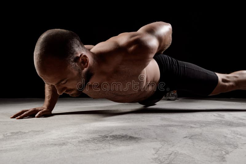 Junger starker Sportler, den Training drückt, ups über dunklen Hintergrund lizenzfreie stockfotografie Junger starker Sportler, den Training drückt, ups über dunklen Hintergrund lizenzfreie stockfotografie