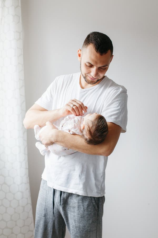 Junger stolzer kaukasischer Vater, der mit neugeborenem Baby spielt. Schwingkindertochtersohn Mannelternteil, das auf Händen hält. lizenzfreie stockfotografie