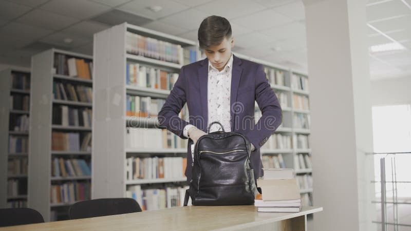 Junger Student kam in die Bibliothek. Männern Student, der Studienforschung in der Bibliothek mit Büchern macht lizenzfreies stockfoto