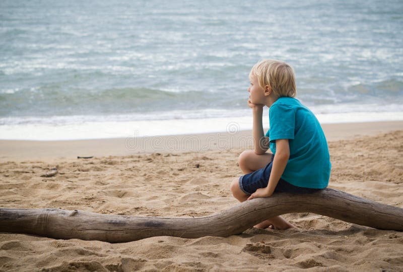 Junger trauriger Junge, der auf dem Strand denkt lizenzfreies stockfoto Junger trauriger Junge, der auf dem Strand denkt lizenzfreies stockfoto