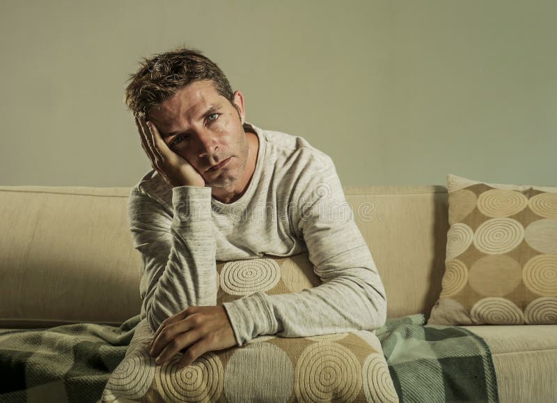 Junger trauriger und hoffnungsloser Mann zu Hause, der an der Sofacouch hält die leidende Krise und Druck des Kissens dem elenden lizenzfreie stockfotos Junger trauriger und hoffnungsloser Mann zu Hause, der an der Sofacouch hält die leidende Krise und Druck des Kissens dem elenden lizenzfreie stockfotos
