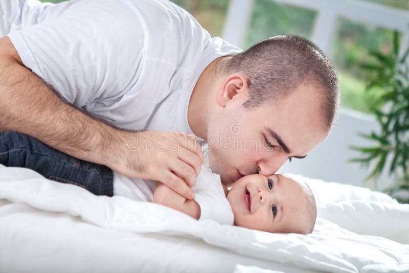 Junger Vater, der seinem Baby einen Kuss gibt stockfotografie Junger Vater, der seinem Baby einen Kuss gibt stockfotografie