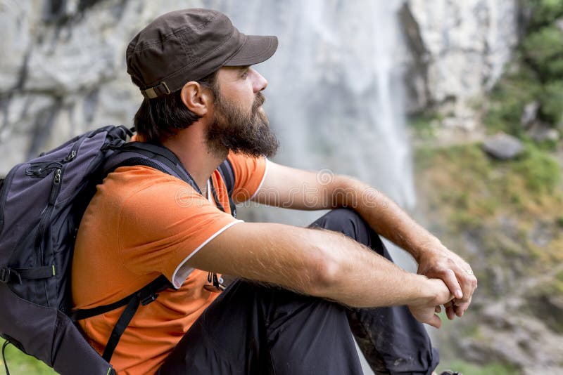 Junger Wanderer, der auf einem Felsen sitzt lizenzfreie stockbilder Junger Wanderer, der auf einem Felsen sitzt lizenzfreie stockbilder