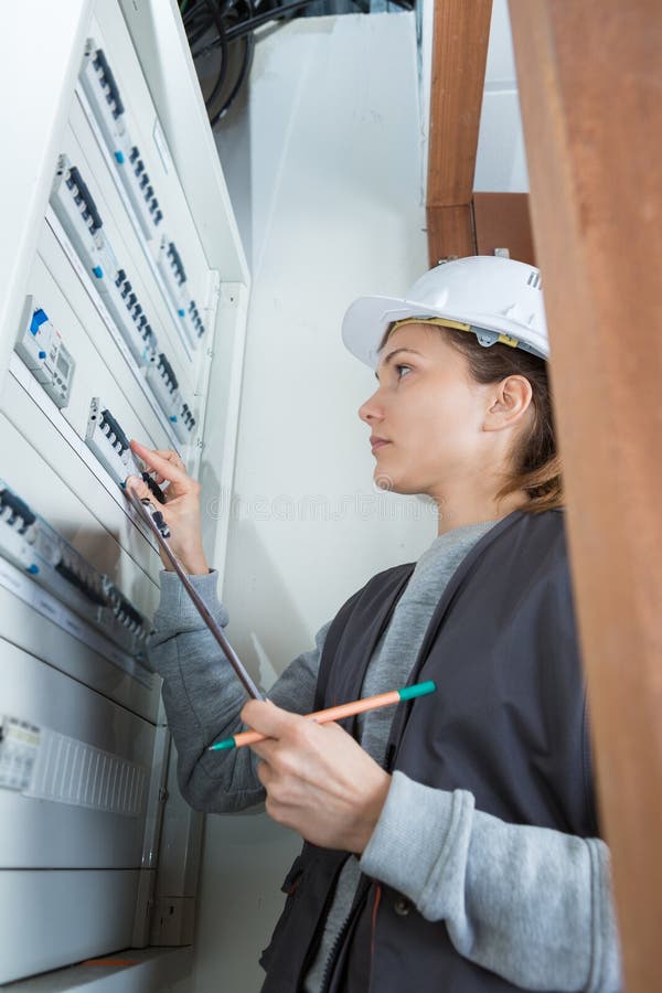 Junger weiblicher Elektriker an der elektrischen Verbrauchereinheit lizenzfreie stockfotografie Junger weiblicher Elektriker an der elektrischen Verbrauchereinheit lizenzfreie stockfotografie