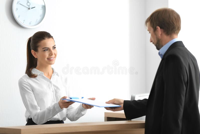 Junger weiblicher Empfangsdamensitzungskunde stockfotografie Junger weiblicher Empfangsdamensitzungskunde stockfotografie