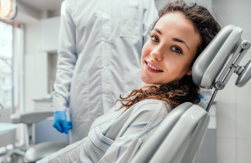 Junger weiblicher Patient, der auf Stuhl im zahnmedizinischen B?ro sitzt Vorbereiten f?r zahnmedizinische Pr?fung Betrachten der lizenzfreie stockfotos Junger weiblicher Patient, der auf Stuhl im zahnmedizinischen B?ro sitzt Vorbereiten f?r zahnmedizinische Pr?fung Betrachten der lizenzfreie stockfotos
