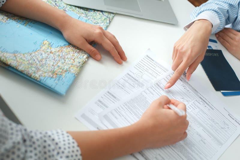 Junger weiblicher Reisebüroberater in der Ausflugagentur mit unterzeichnenden Dokumenten eines Kunden