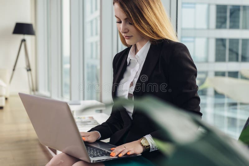 Junger weiblicher Werbetexter, der einen Werbetext schreibt auf die Laptoptastatur sitzt in Büro schreibt