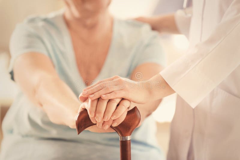 Junges Doktorhändchenhalten der älteren Frau lizenzfreie stockbilder Junges Doktorhändchenhalten der älteren Frau lizenzfreie stockbilder