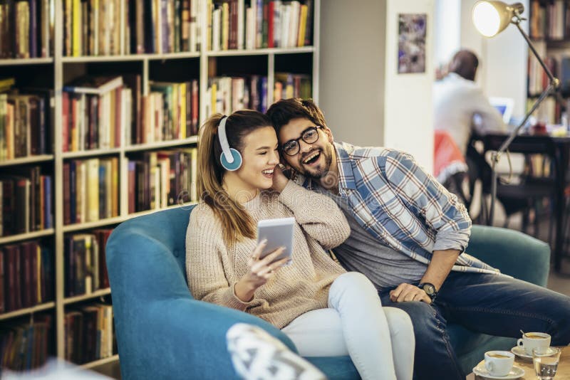 Junges Ehepaar saß im Café und trank Kaffee und hörte Musik mit Smartphone stockfotos