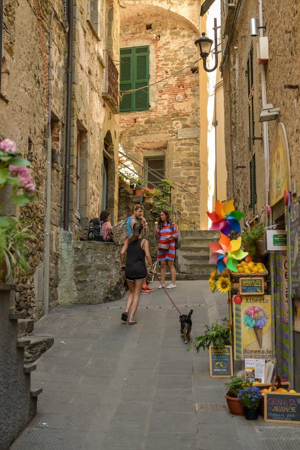 Junges gehendes Mädchen ihr Hund durch schmale Straßen in Corniglia lizenzfreie stockfotografie Junges gehendes Mädchen ihr Hund durch schmale Straßen in Corniglia lizenzfreie stockfotografie