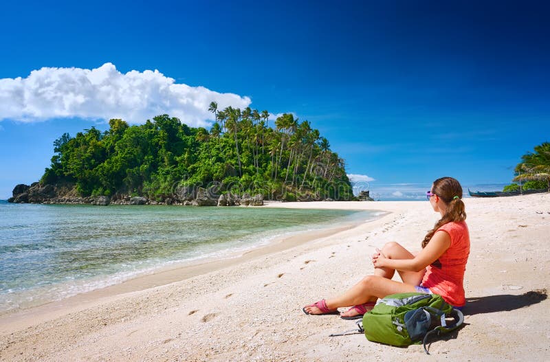 Junges gerl mit dem Rucksack, der auf Küste sich entspannt und zu einem isla schaut stockbild Junges gerl mit dem Rucksack, der auf Küste sich entspannt und zu einem isla schaut stockbild