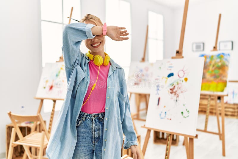 Young caucasian girl at art studio covering eyes with arm smiling cheerful and funny. blind concept. Young caucasian girl at art studio covering eyes with arm smiling cheerful and funny. blind concept