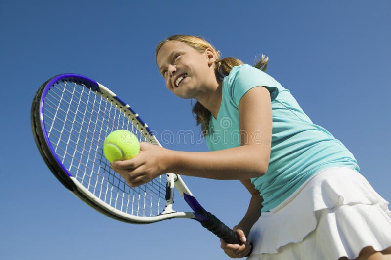 Junges Mädchen auf dem Tennisplatz, der sich vorbereitet, niedrigen Winkelsichtabschluß oben zu dienen stockbild