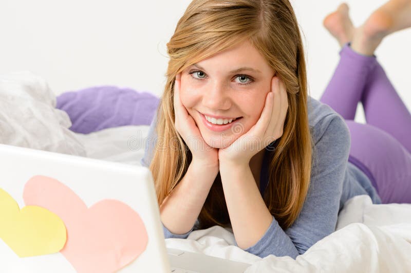 Junges Mädchen, das auf Bett mit Laptop liegt stockfotografie Junges Mädchen, das auf Bett mit Laptop liegt stockfotografie
