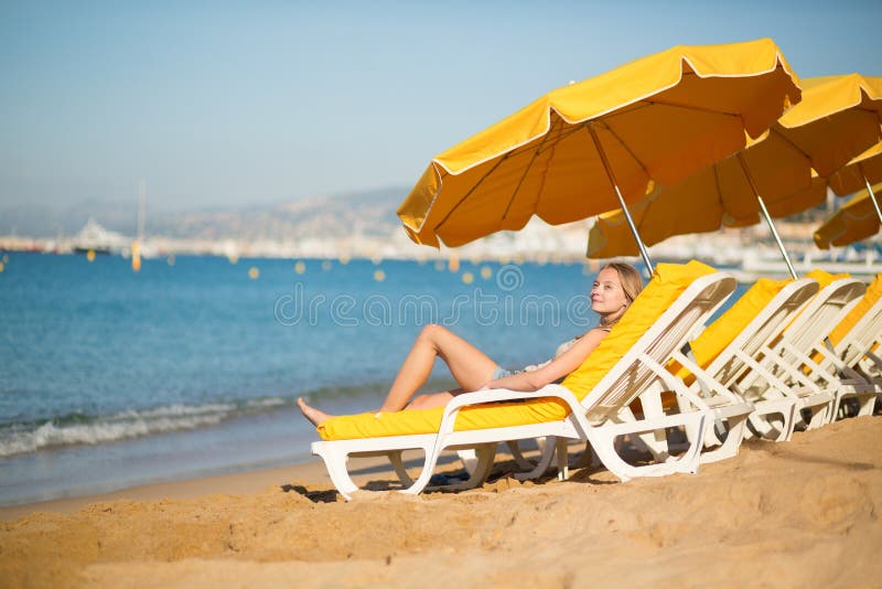 Junges Mädchen, das auf einem Strandstuhl nahe dem Meer sich entspannt lizenzfreies stockfoto Junges Mädchen, das auf einem Strandstuhl nahe dem Meer sich entspannt lizenzfreies stockfoto
