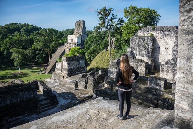 Junges Mädchen, das Mayaruinen bei Tikal, Nationalpark erwägt Tr