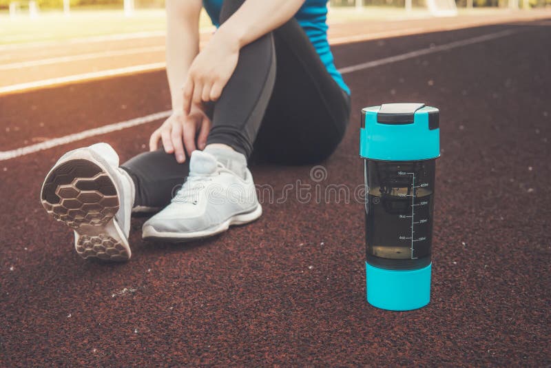 Junges Mädchen, das sich mit Proteindrink- oder Wasserflasche auf Straße nach laufender Trainingsstraße der laufenden Übung hinse stockfotos Junges Mädchen, das sich mit Proteindrink- oder Wasserflasche auf Straße nach laufender Trainingsstraße der laufenden Übung hinse stockfotos
