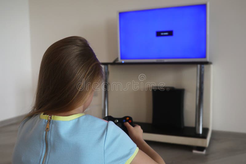 Junges Mädchen, das vor dem Fernsehen spielt lizenzfreies stockfoto Junges Mädchen, das vor dem Fernsehen spielt lizenzfreies stockfoto