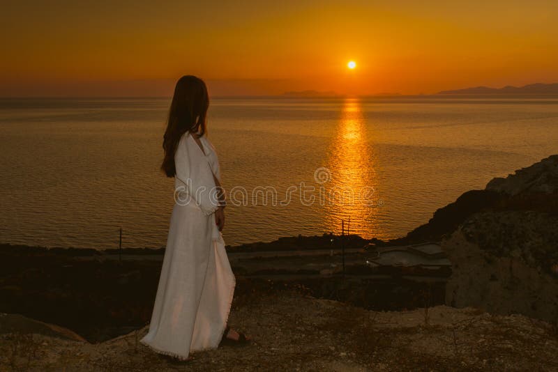 Junges Mädchen am Rand einer Klippe in einem weißen Kleid den Sonnenuntergang in Santorini, Griechenland aufpassend Frau in den w stockfotos Junges Mädchen am Rand einer Klippe in einem weißen Kleid den Sonnenuntergang in Santorini, Griechenland aufpassend Frau in den w stockfotos