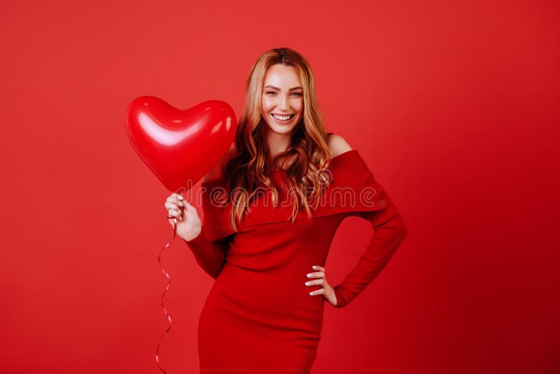 Junges reizend Mädchen mit dem langen gelockten Haar, im roten Kleid, das die Luftballone, werfend an der Kamera hält auf stockfotos Junges reizend Mädchen mit dem langen gelockten Haar, im roten Kleid, das die Luftballone, werfend an der Kamera hält auf stockfotos