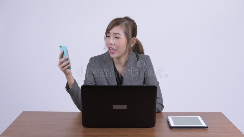 Junges schönes asiatisches Geschäftsfrauvideo, das bei der Arbeit nennt