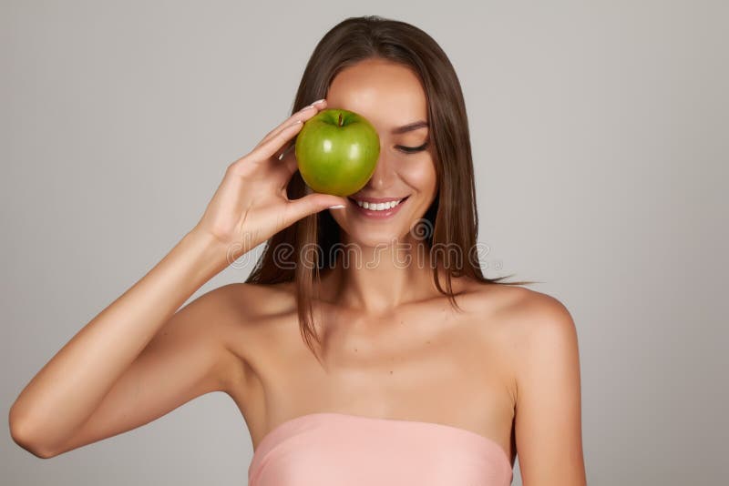Junges schönes sexy Mädchen mit dem dunklen gelockten Haar, den bloßen Schultern und dem Hals, großen grünen Apfel halten, um den stockfotos Junges schönes sexy Mädchen mit dem dunklen gelockten Haar, den bloßen Schultern und dem Hals, großen grünen Apfel halten, um den stockfotos