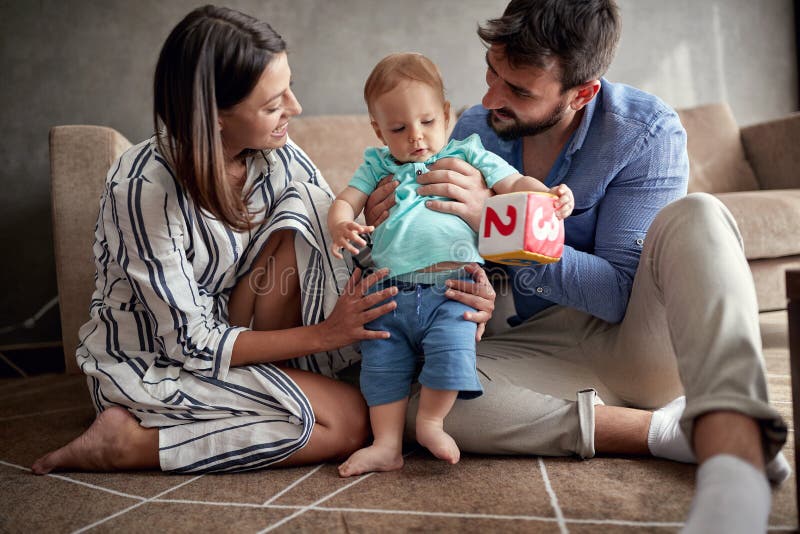 Junges stolzes Familienspielen und -baby lernend, zu Hause zu gehen stockbild