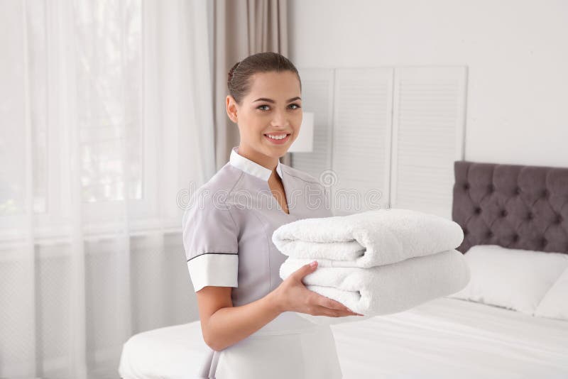 Junges Stubenmädchen mit sauberen Tüchern lizenzfreies stockfoto Junges Stubenmädchen mit sauberen Tüchern lizenzfreies stockfoto