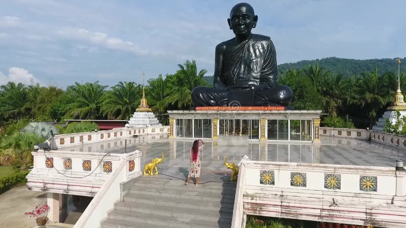 Junges touristisches Mädchen, das herauf die Treppe zu sitzender meditierender schwarzer Mönchstatue im buddhistischen Tempel geh stock video
