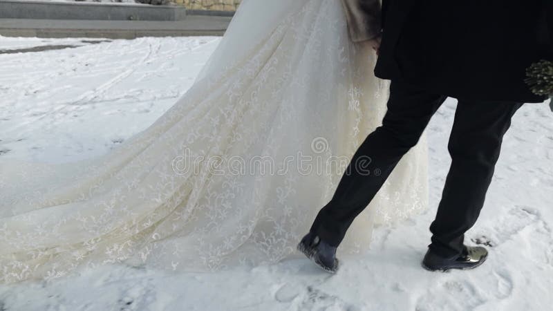 Jungvermählten. Braut und Bräutigam, die zusammen auf Schnee gehen.. Hochzeitspaare