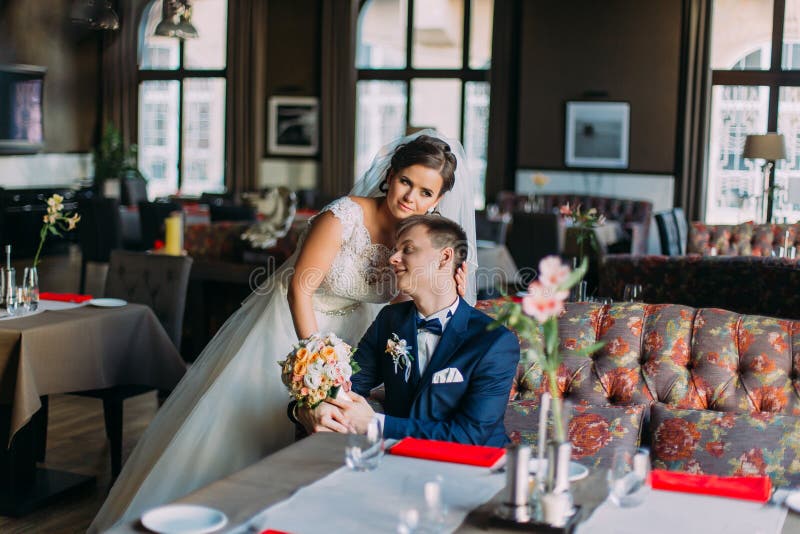 Jungvermählten enloved Paare Reizend Braut im weißen Kleid, das nahe dem hübschen stylishgroom zuhause aufwirft, Luxus hell steht lizenzfreies stockfoto Jungvermählten enloved Paare Reizend Braut im weißen Kleid, das nahe dem hübschen stylishgroom zuhause aufwirft, Luxus hell steht lizenzfreies stockfoto
