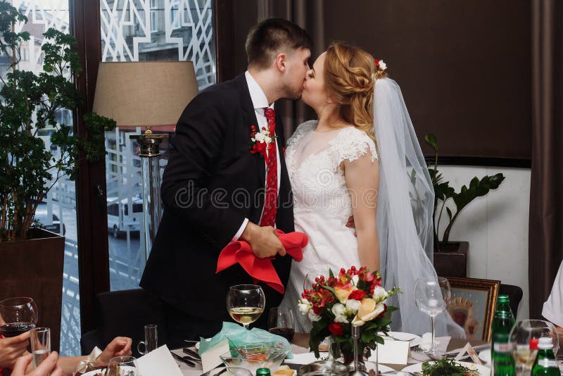 Jungvermähltenpaare, die am Hochzeitsempfang im Restaurant, brid küssen lizenzfreie stockfotos Jungvermähltenpaare, die am Hochzeitsempfang im Restaurant, brid küssen lizenzfreie stockfotos
